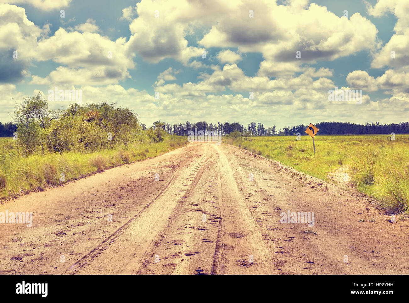 Tournez à gauche au panneau jaune noir avec de la terre chemin de sable en campagne. Cinematic road landcape. L'Argentine. L'Amérique du Sud Banque D'Images