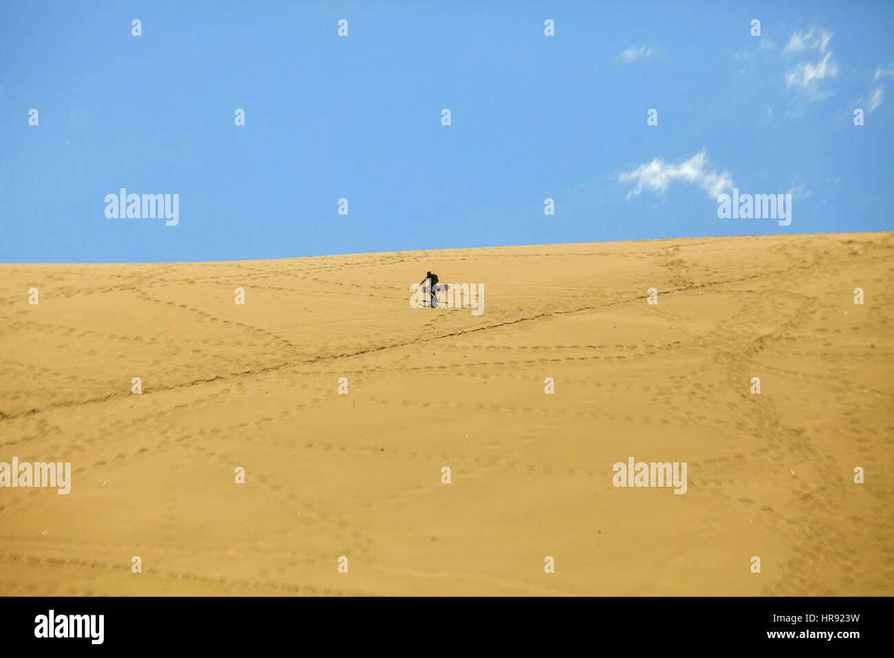 Man climbing with surfboard en haut de la dune Banque D'Images