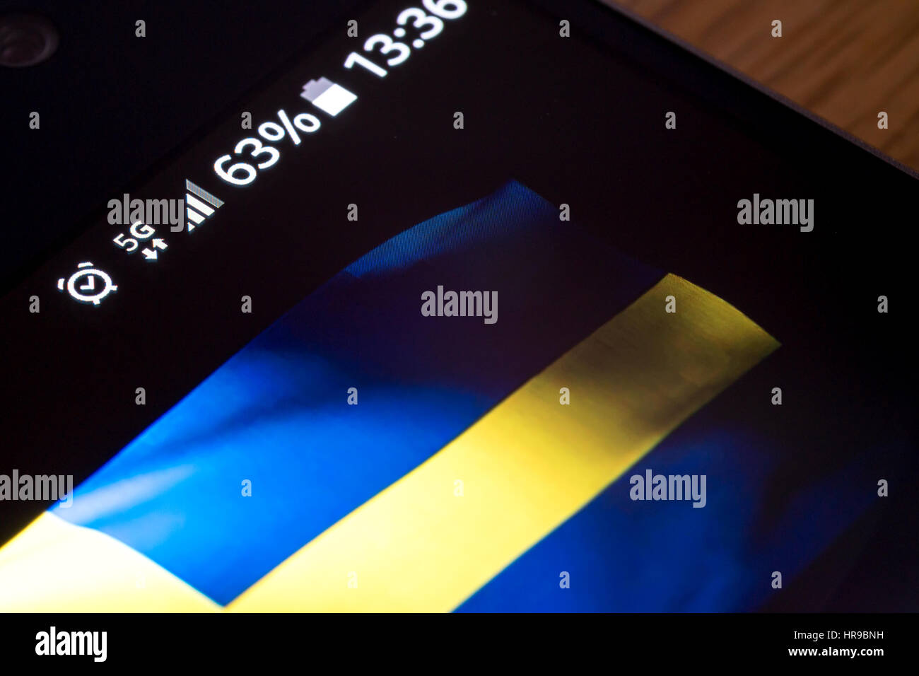 Smartphone sur fond de bois avec 4G Réseau inscription 25  % et la Suède drapeau sur l'écran. Banque D'Images