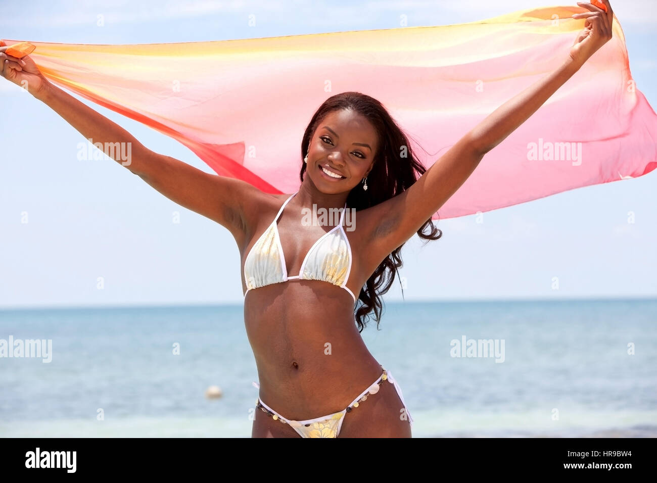 Femme noire de plage avec un sarong dans ses mains, sentant le vent Banque D'Images