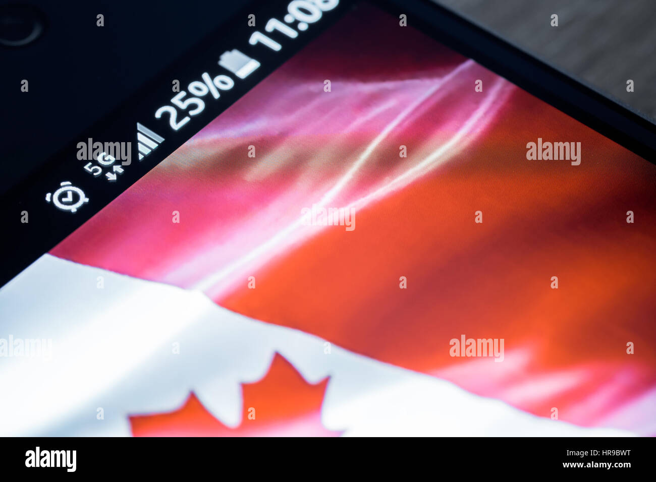 Sur fond de bois avec smartphone 5G Réseau inscription 25  % et le Canada drapeau sur l'écran. Banque D'Images