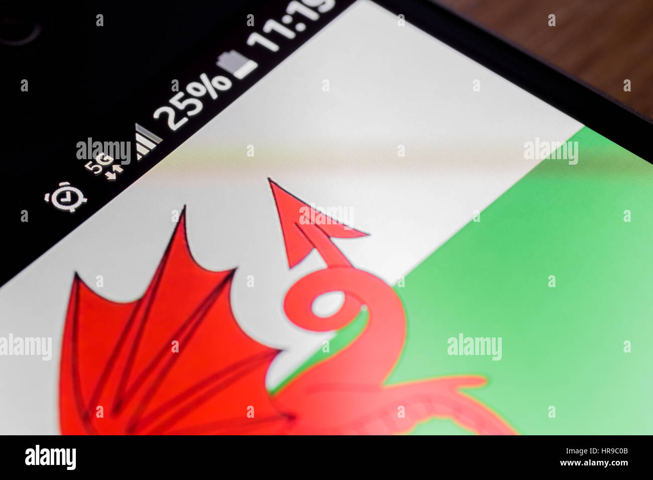 Sur fond de bois avec smartphone 5G Réseau inscription 25  % et le Pays de Galles drapeau sur l'écran. Banque D'Images