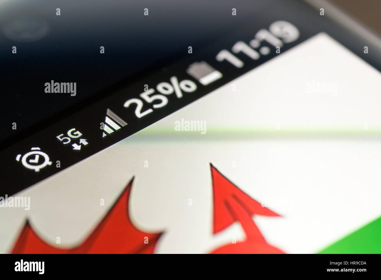 Sur fond de bois avec smartphone 5G Réseau inscription 25  % et le Pays de Galles drapeau sur l'écran. Banque D'Images