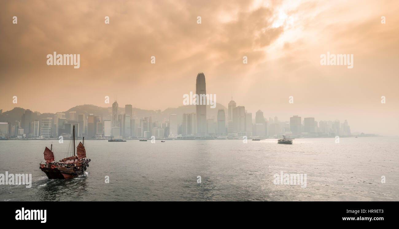 Ancien navire chinois traditionnels avec les touristes qui navigue dans le port de Victoria avec les gratte-ciel et l'horizon de Hong Kong. La Chine. Banque D'Images