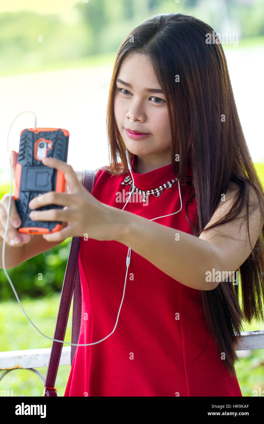 Jeune fille en robe rouge de prendre un smartphone avec selfies Banque D'Images