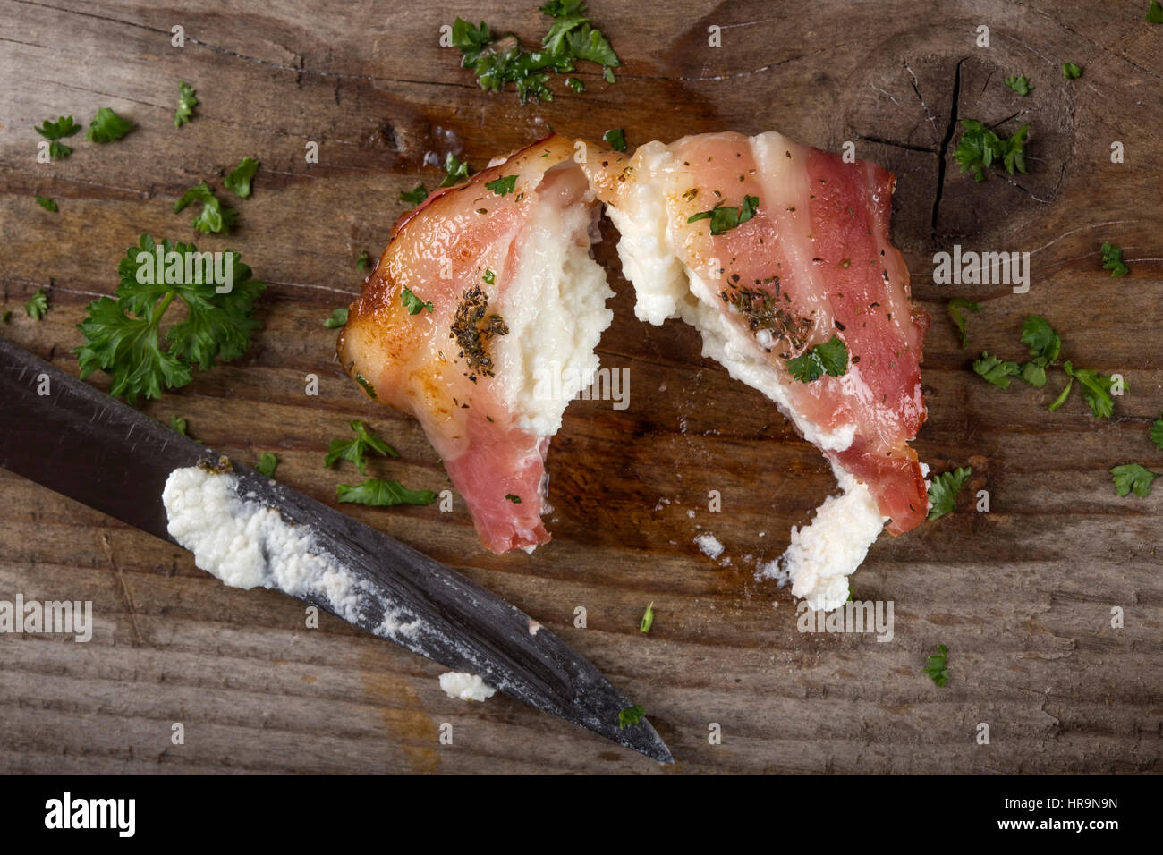 Fromage de chèvre frit enroulé dans le bacon fumé sur bois avec couteau et le persil Banque D'Images