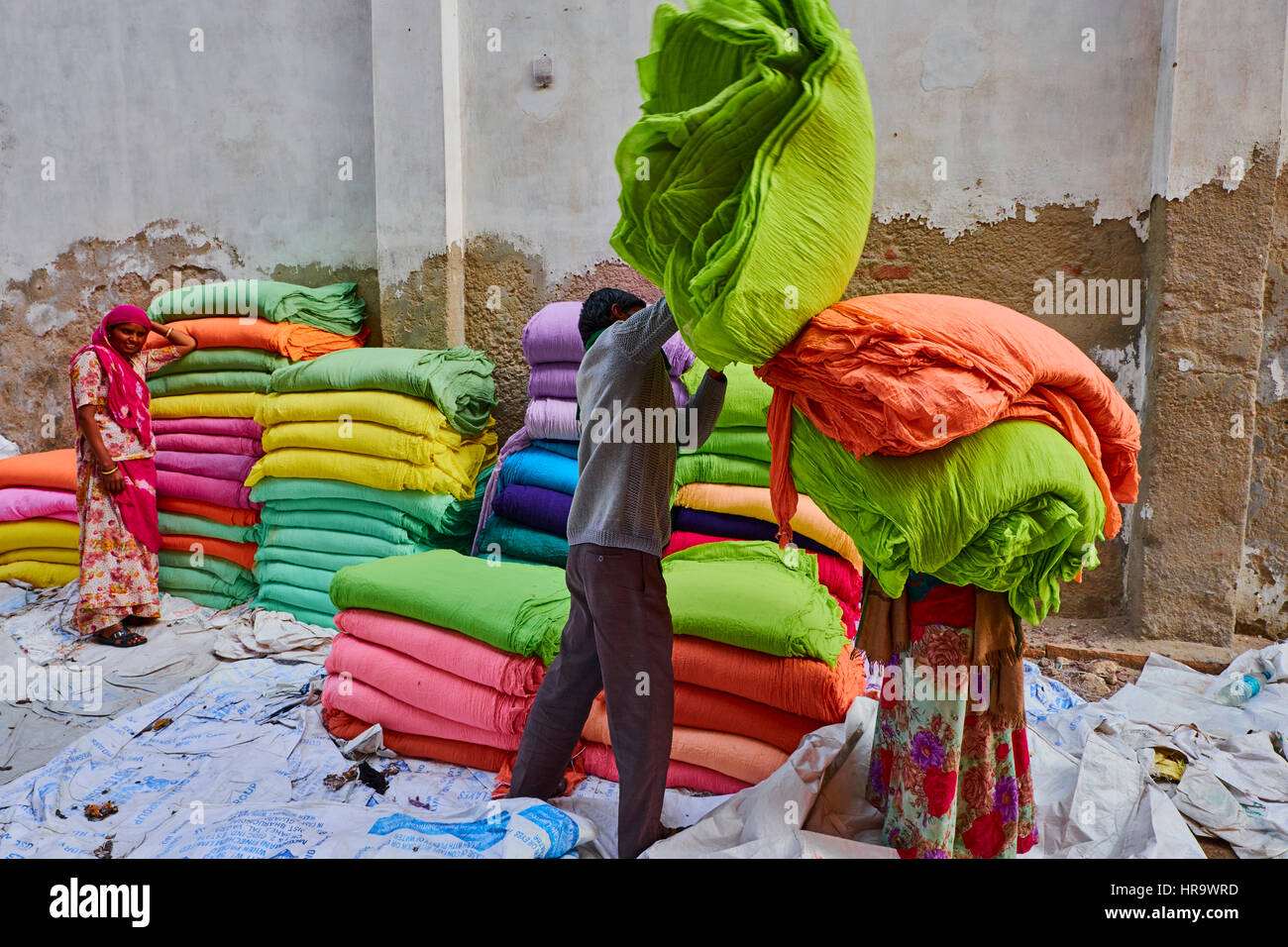 L'Inde, Rajasthan, Sari, usine textile sont séchés à l'air libre. La collecte des textiles à sec sont pliées par les femmes. Les tissus sont suspendus pour le séchage sur bamb Banque D'Images