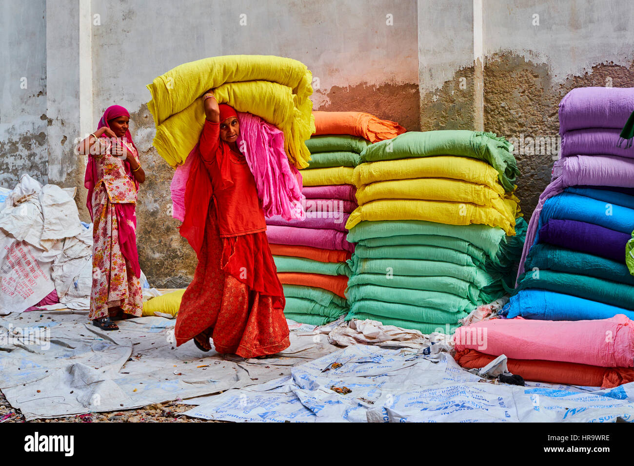 L'Inde, Rajasthan, Sari, usine textile sont séchés à l'air libre. La collecte des textiles à sec sont pliées par les femmes. Les tissus sont suspendus pour le séchage sur bamb Banque D'Images