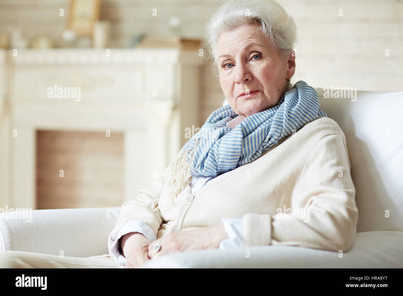 Portrait of woman looking at camera à la retraite avec des yeux d'un bleu profond tout en restant assis dans une belle salle de séjour Banque D'Images