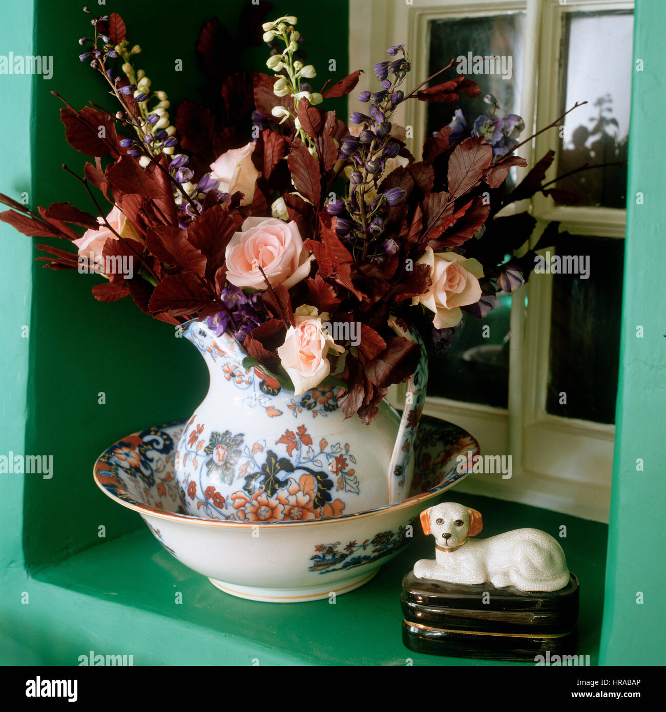 Roses dans un pot sur un rebord de fenêtre. Banque D'Images