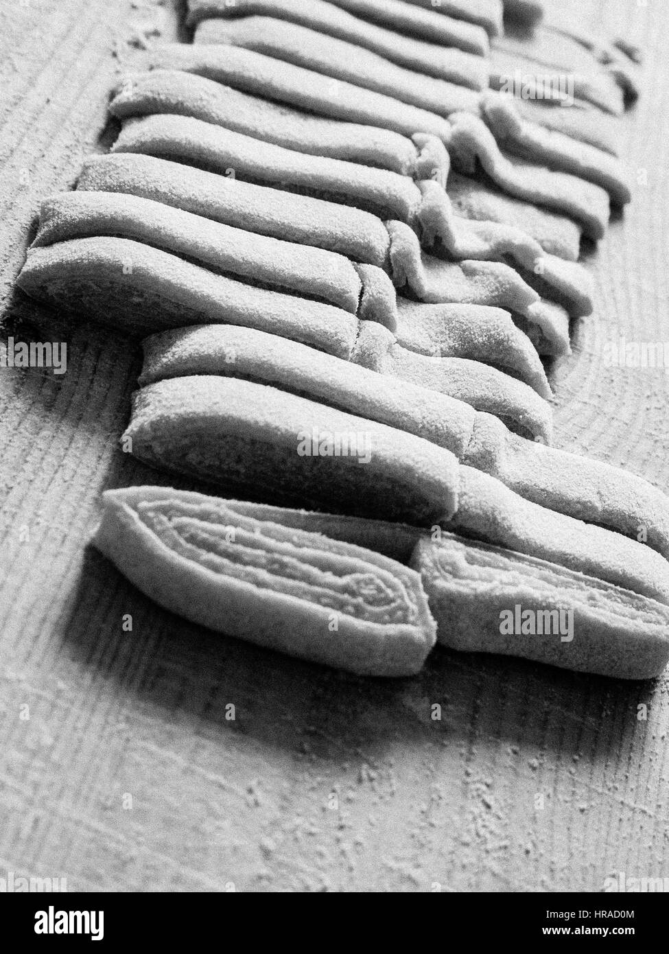 La pâte des pâtes et des tranches de roulé pour créer les fettuccine dans la manière traditionnelle Banque D'Images