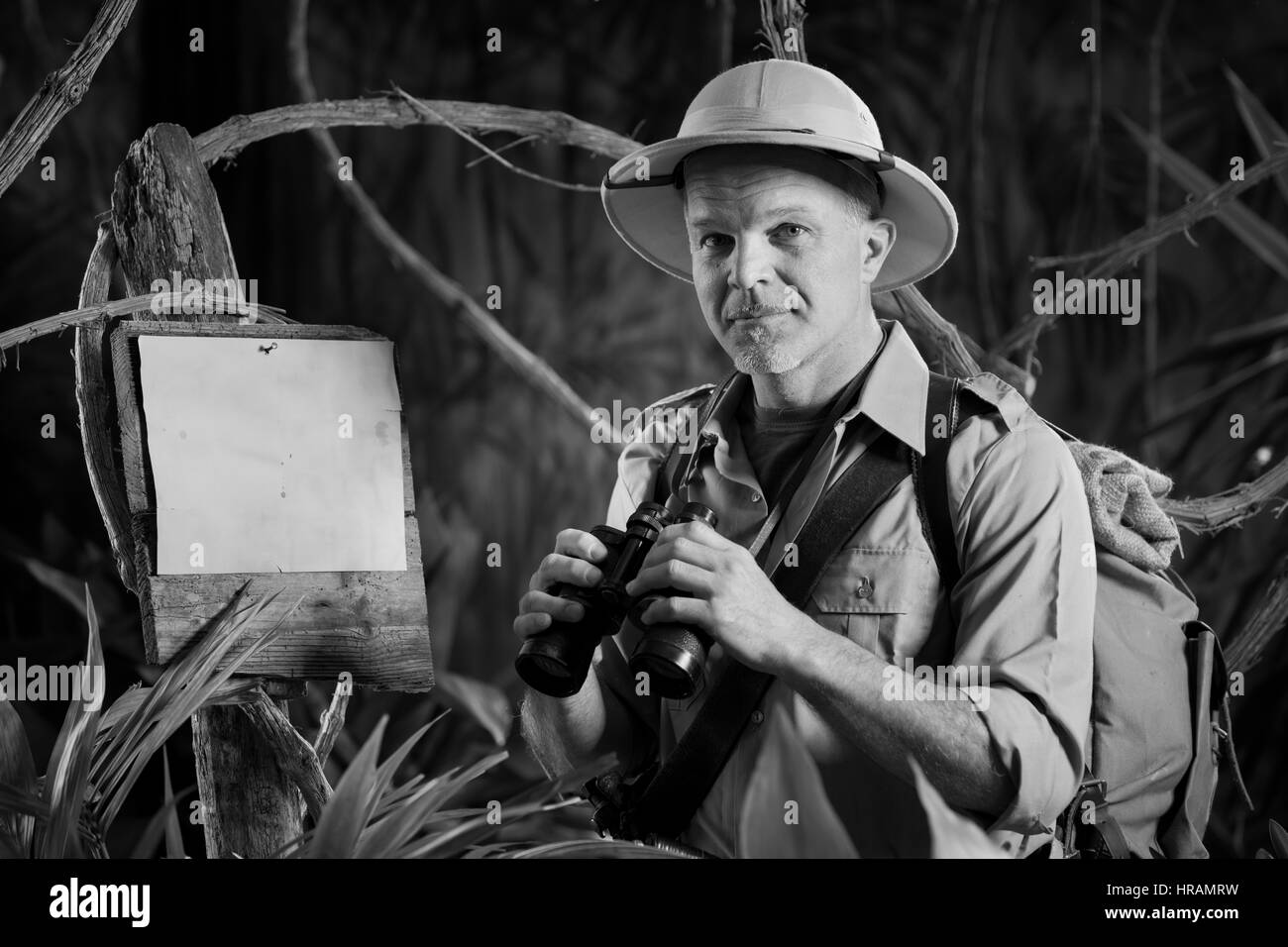 Smiling explorer dans le style colonial de l'habillement holding binoculars et à la recherche à l'appareil photo. Banque D'Images
