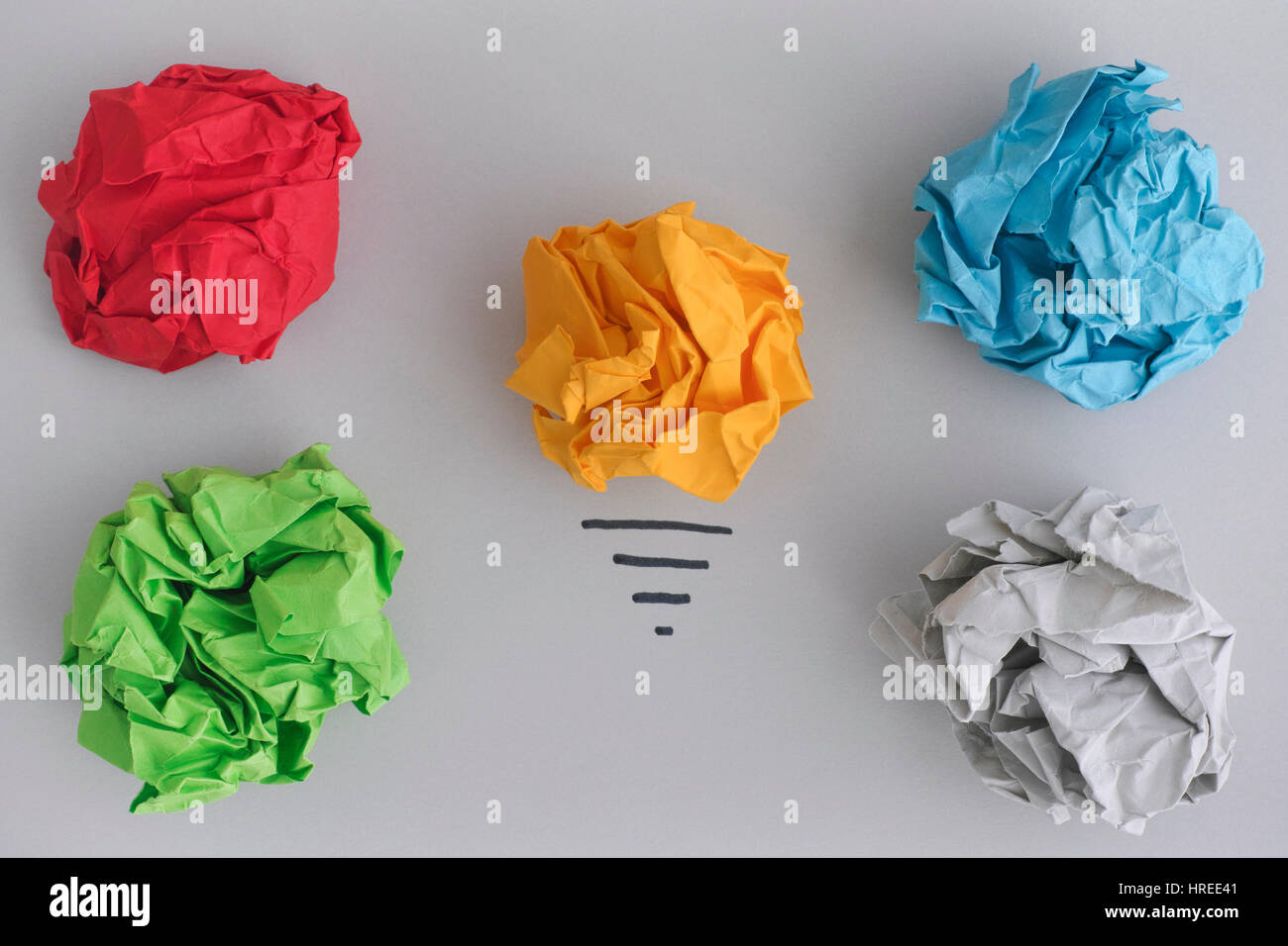 À la recherche de nouvelles idées ou innovations. Boule de papier froissé jaune comme une ampoule et boules de papier froissé coloré. Banque D'Images