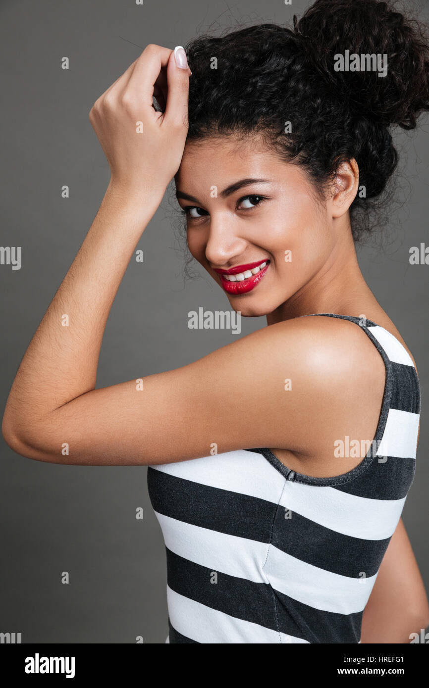 Cheerful charmante jeune femme afro-américaine avec des lèvres rouges sur fond gris Banque D'Images