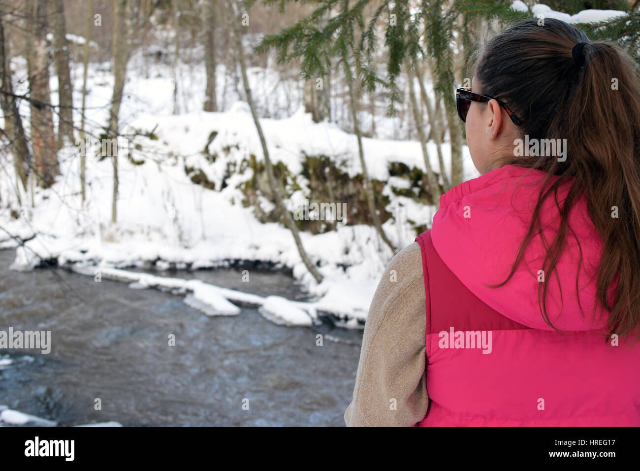 Jeune femme regardant creek sur la forêt d'hiver. Banque D'Images