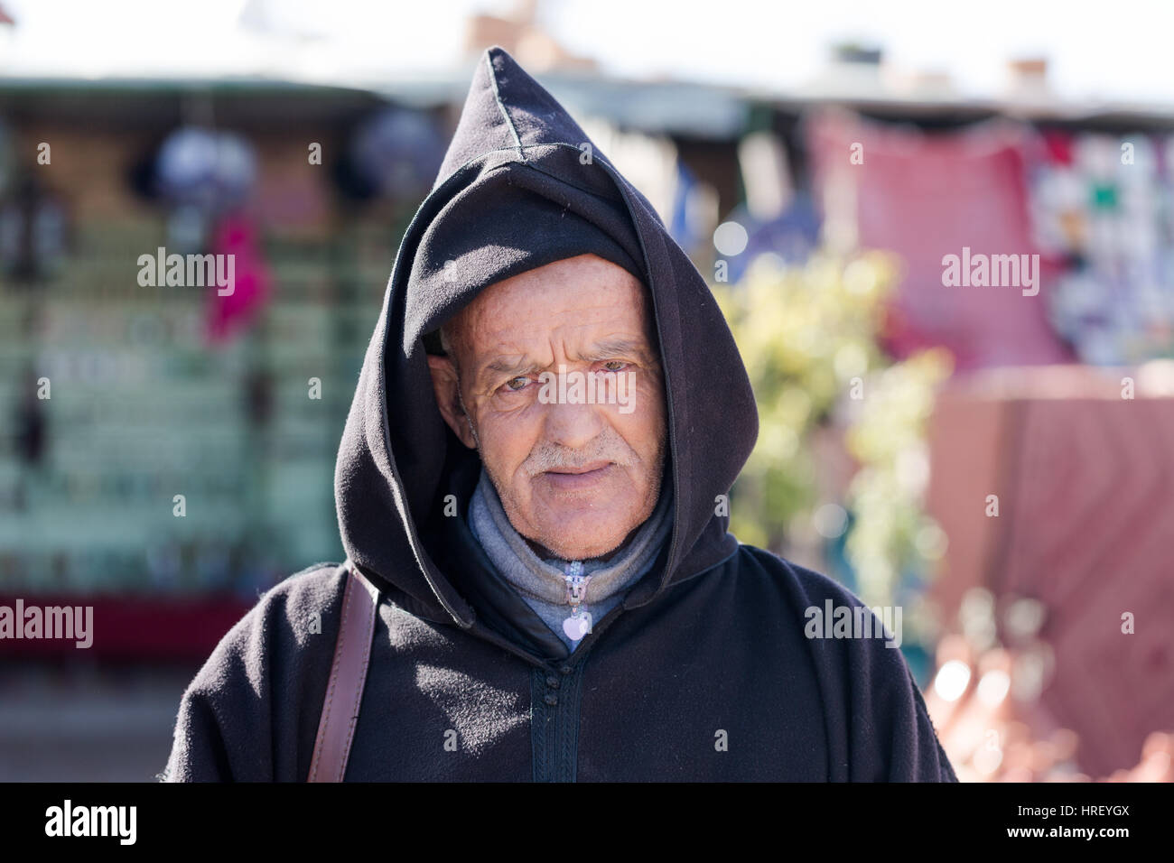 Morrocan pauvres vieil homme portrait. Vêtu du costume traditionnel hooded cloak. La vente du vendeur routière marchandises bon marché. Vu le 16 février 2017 à l'extérieur de Marrakech Banque D'Images