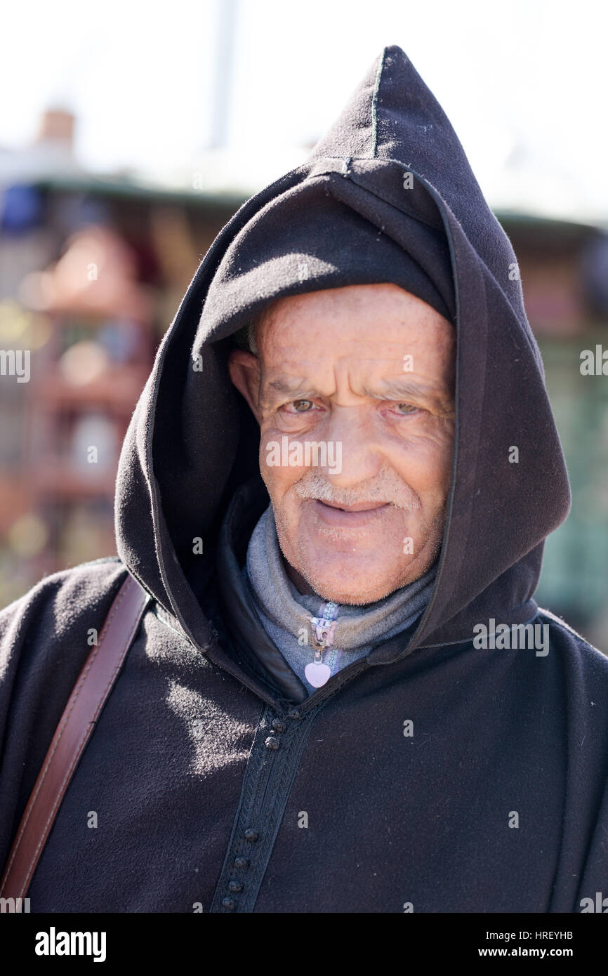 Morrocan pauvres vieil homme portrait. Vêtu du costume traditionnel hooded cloak. La vente du vendeur routière marchandises bon marché. Vu le 16 février 2017 à l'extérieur de Marrakech Banque D'Images