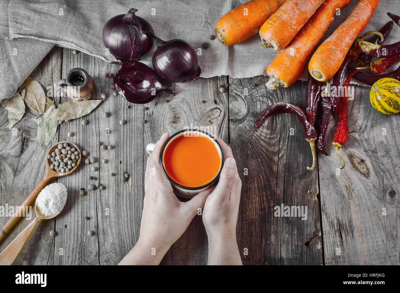 Tasse de jus de carotte dans les mains sur une surface en bois gris, vue du dessus Banque D'Images