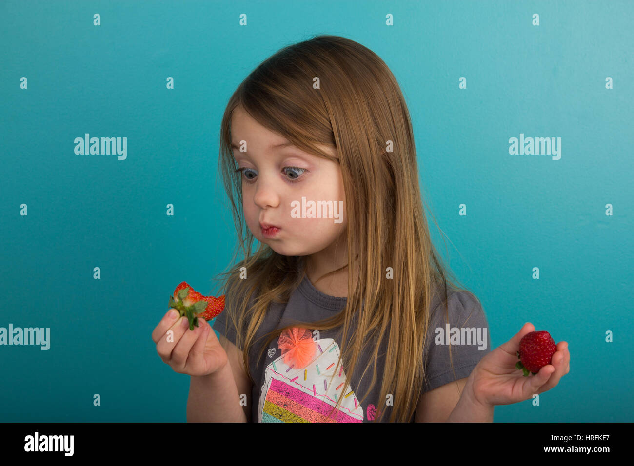 Dégustation de fraises une petite fille Banque D'Images