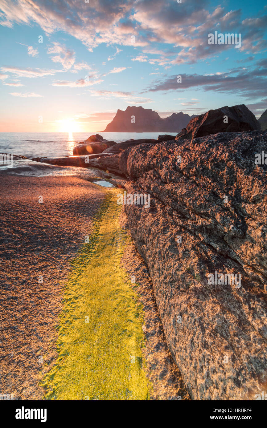 Lumières du soleil de minuit sur les rochers entourant la mer bleue, Uttakleiv, îles Lofoten, dans le Nord de la Norvège, Scandinavie Banque D'Images