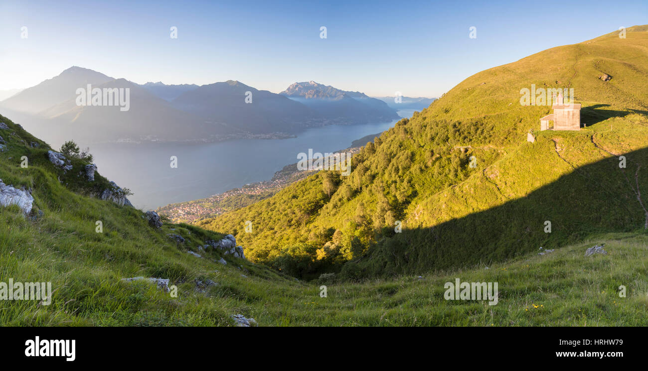 Soleil sur l'église de San Bernardo allume le paysage autour de l'eau bleu du lac de Côme à l'aube, Musso, Lombardie, Italie Banque D'Images