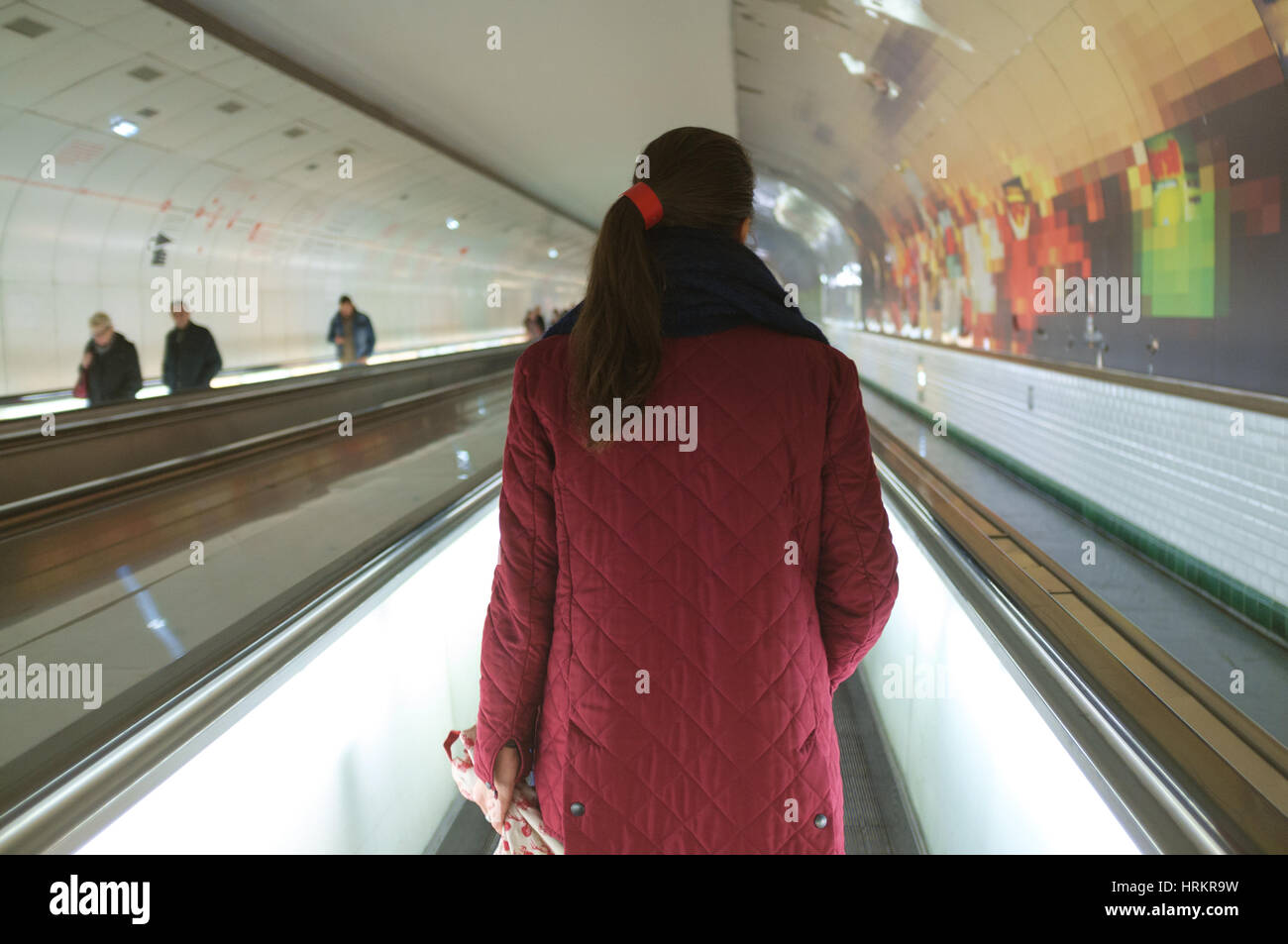 Vue arrière d'une femme en rouge, marchant dans un tapis roulant (tapis roulant) dans le métro à Paris Banque D'Images
