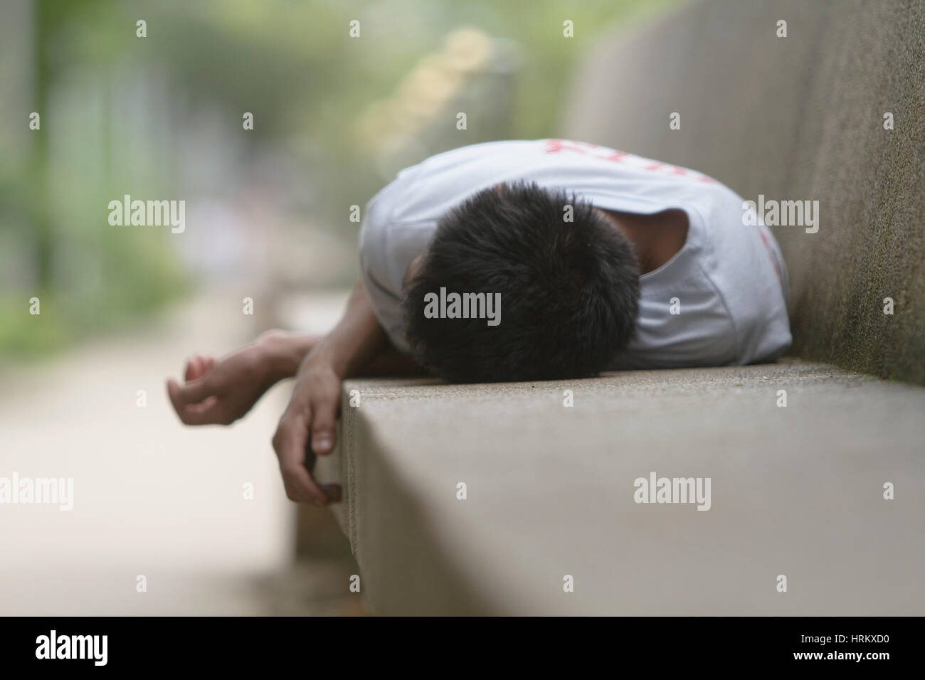 L'homme de dormir sur un banc en béton Banque D'Images
