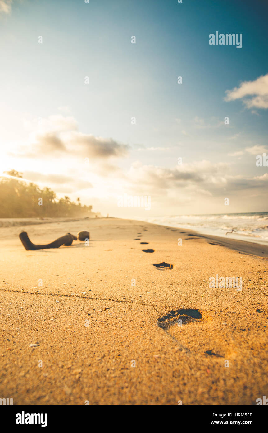 Des traces de pas dans le sable à la plage par le coucher du soleil Banque D'Images