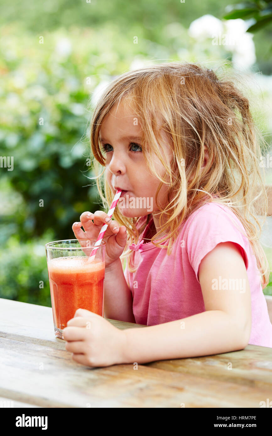 Girl drinking smoothy de fruits avec une paille Banque D'Images