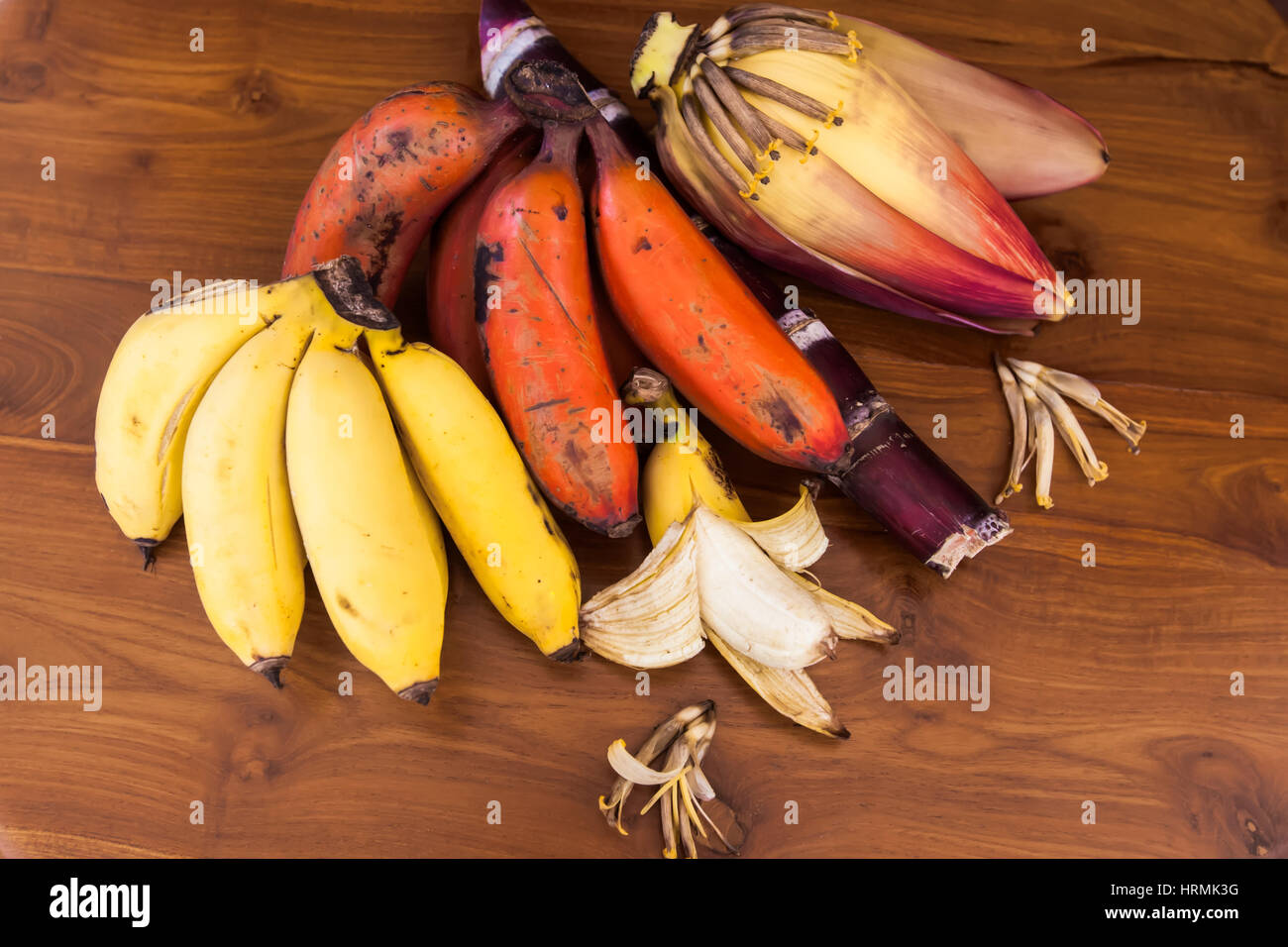 La banane jaune et rouge frais et grappes de bananes non mûres sur table en bois Banque D'Images