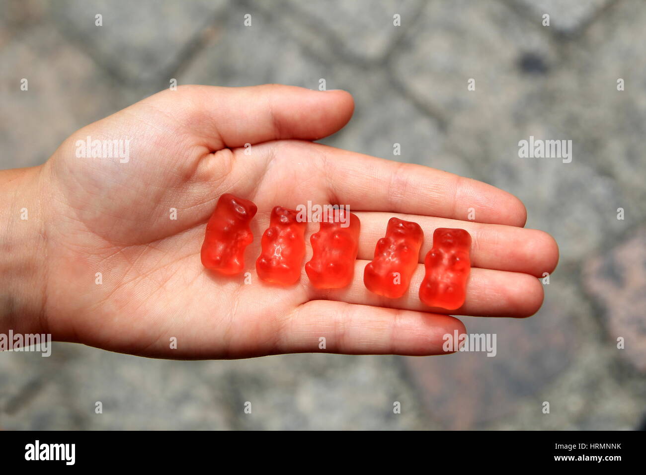 La main de l'enfant ouvrir palmed holding cinq ours gummi rouge Banque D'Images