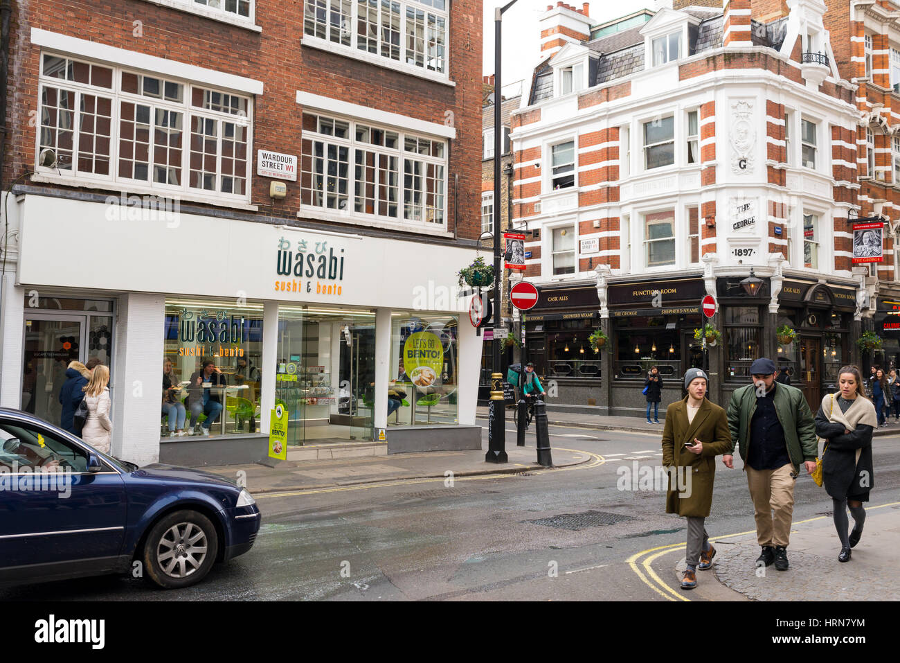 Les gens qui marchent dans Wardour Street, Soho en face d'une antenne locale de le restaurant japonais Wasabi. London, UK Banque D'Images