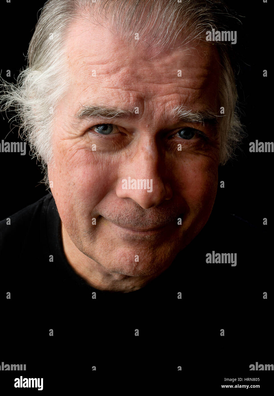 Close up portrait of head shot of a senior man dans ses 50 ans. homme portant des T-shirt noir et isolé sur fond noir. Banque D'Images