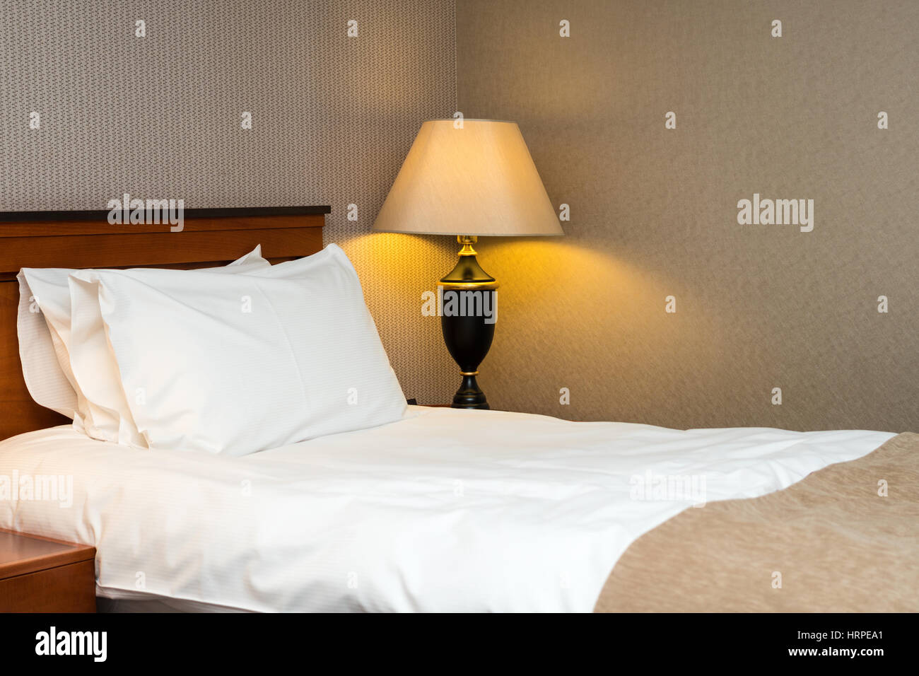 Deux oreillers sur le lit et lampe sur table en bois dans la chambre d'hôtel Banque D'Images