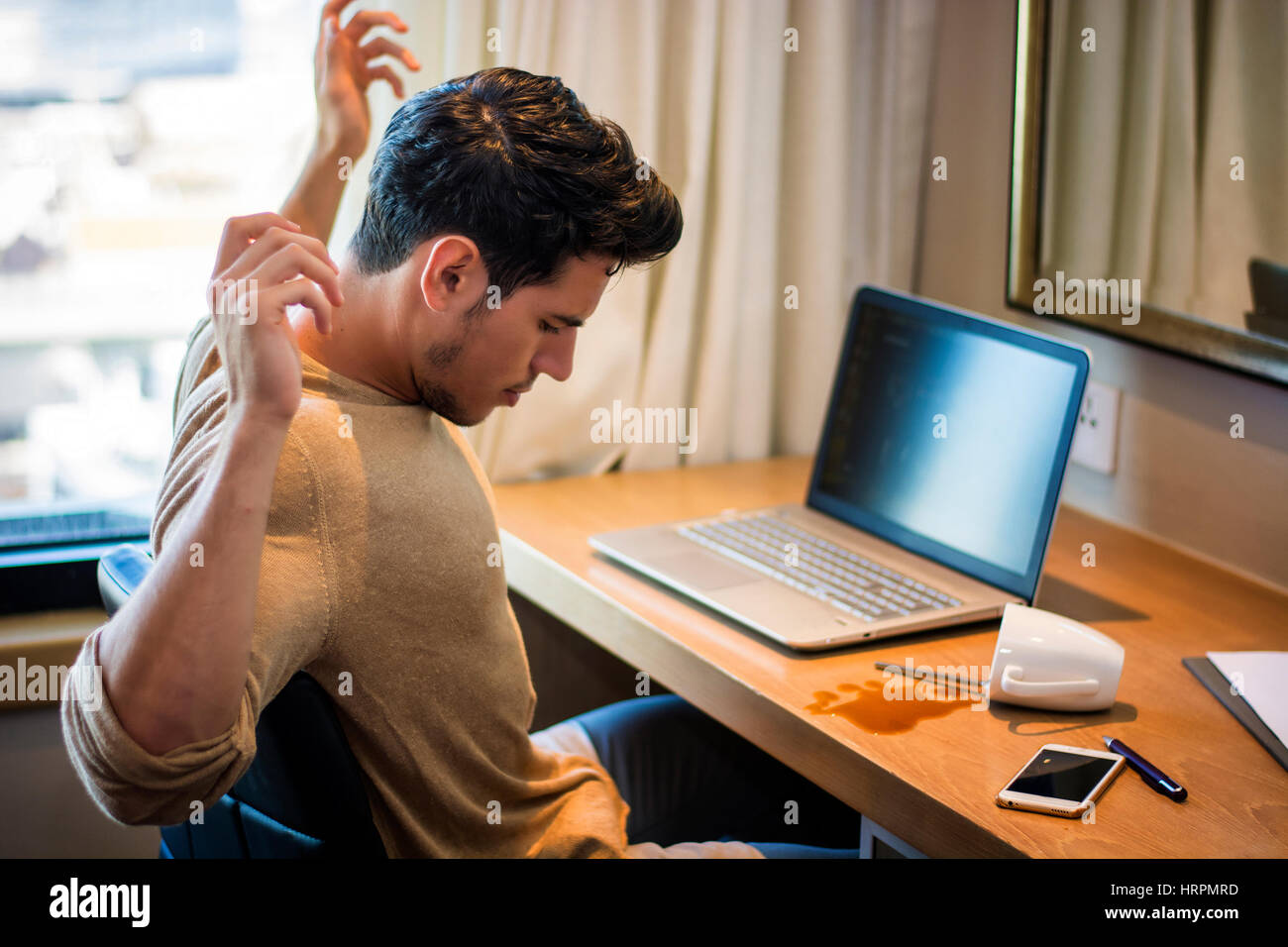 L'homme assis à la table renversé sa tasse de café. L'intérieur horizontal tourné. Banque D'Images L'homme assis à la table renversé sa tasse de café. L'intérieur horizontal tourné. Banque D'Images