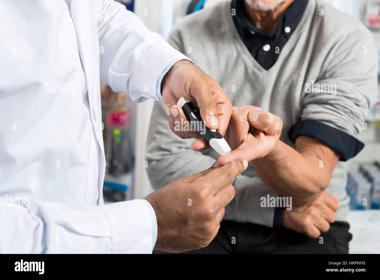 Au milieu de l'homme médecin contrôle de niveau de sucre senior patient avec glucomètre en pharmacie Banque D'Images