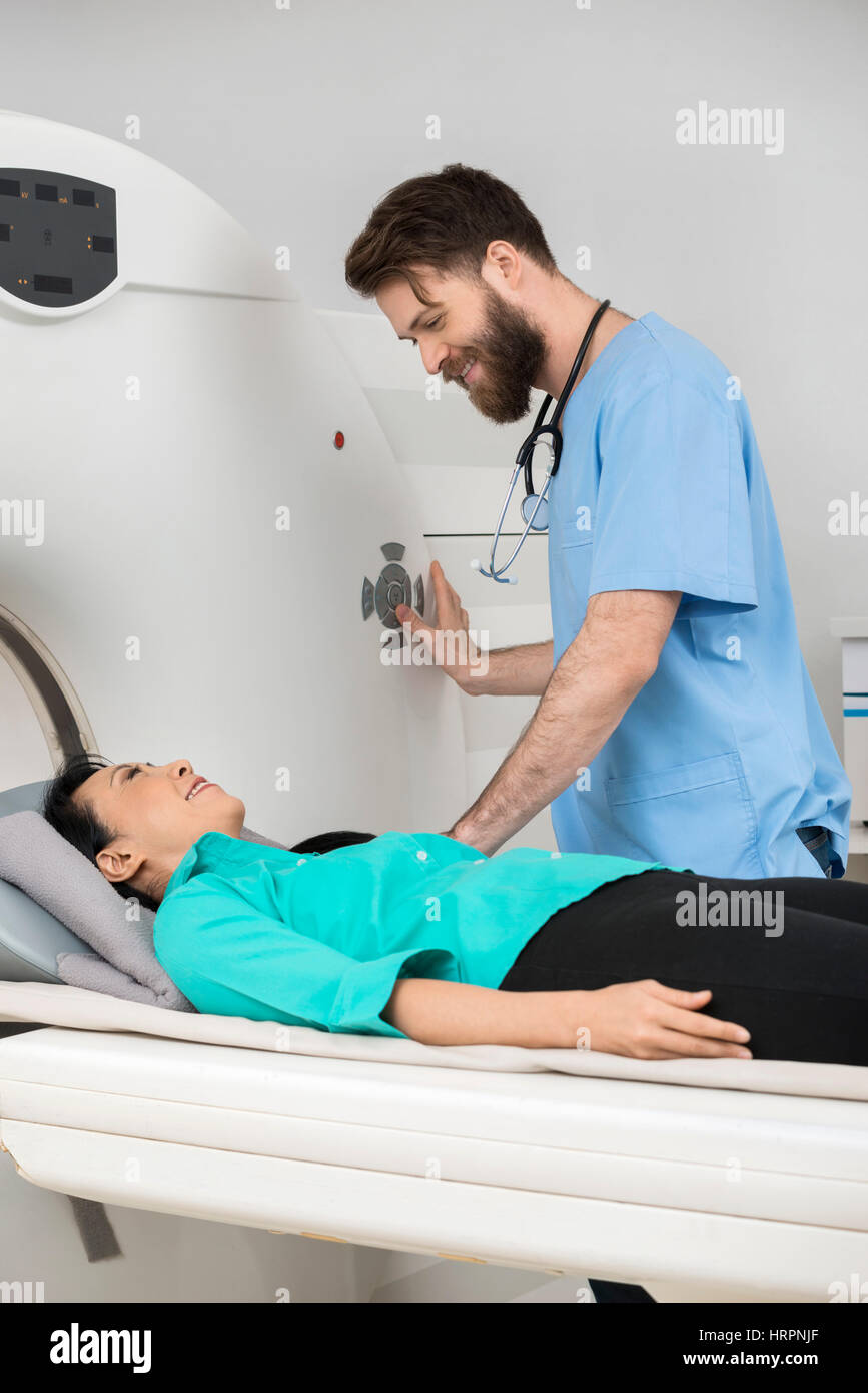 Jeune homme médecin sur le point de commencer ct scan sur female patient in examination room Banque D'Images