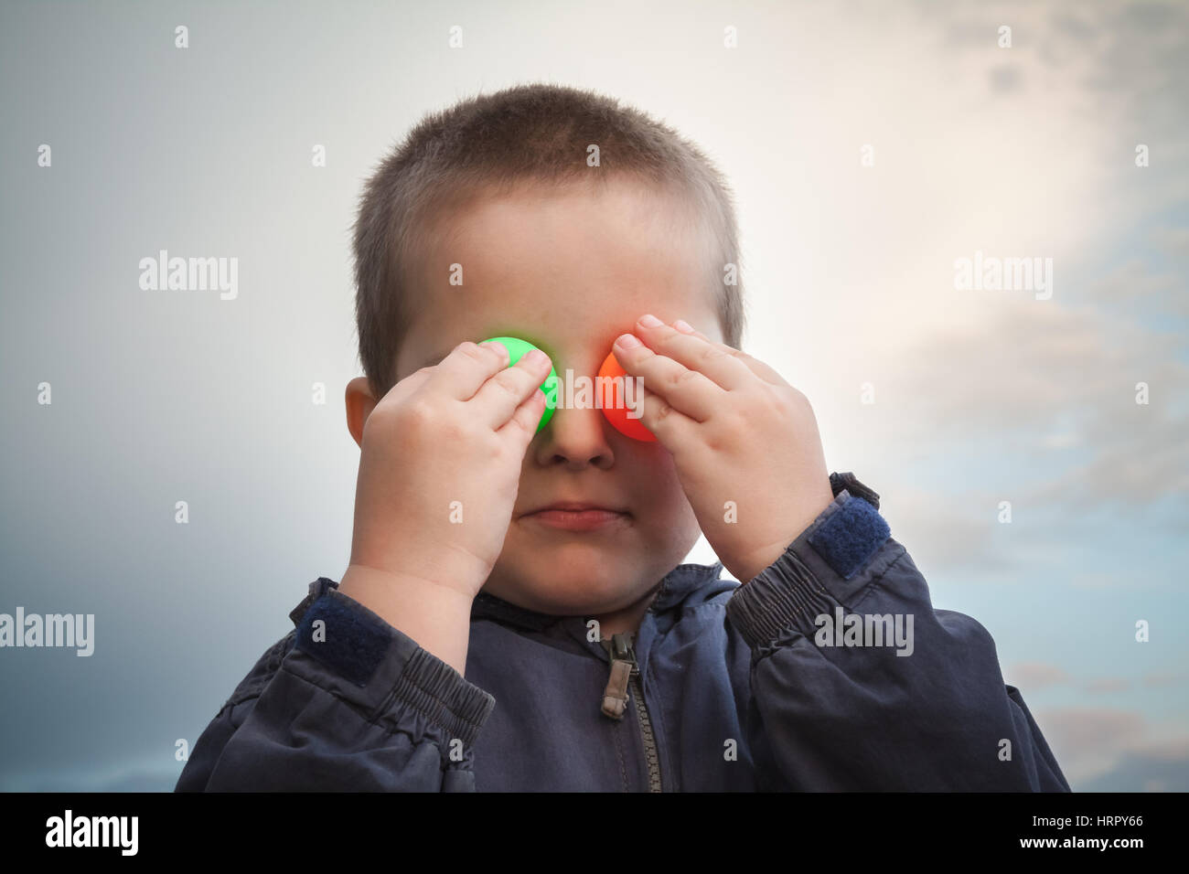 Enfant jouant avec balle de ping-pong de couleur making faces Banque D'Images