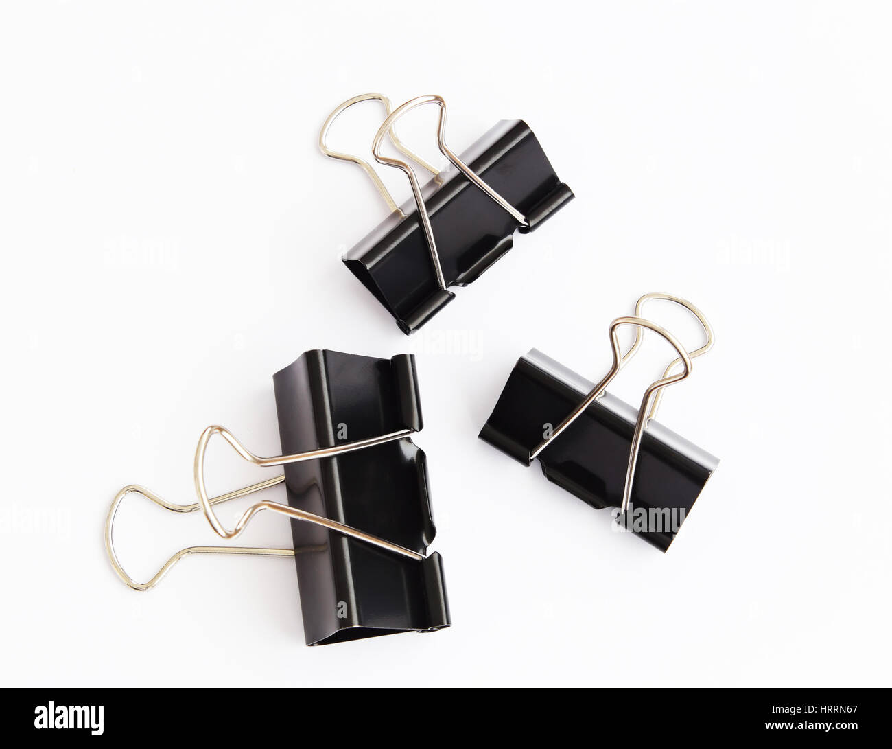Clips pour le papier noir isolé sur fond blanc. Arrière-plan de bureau parfait. Outils de bureau pour papier. Bureau noir acier trois clips. Banque D'Images