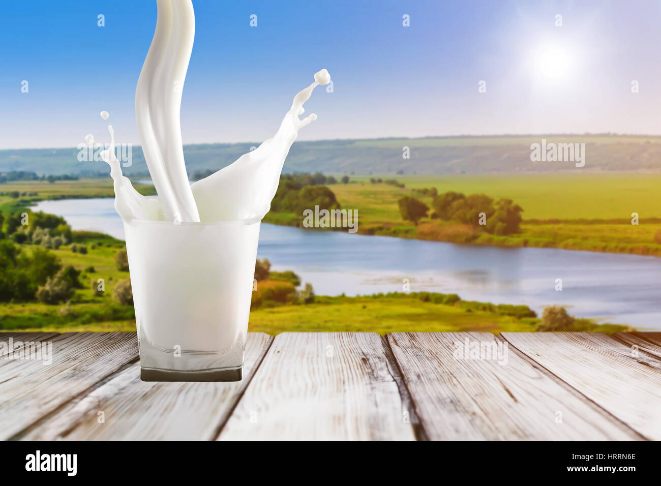 Verser le lait dans le verre. Close up de lait splash. Lait dans le verre sur la table en bois. Avec verre de lait blanc sur fond de sunrise. Arrière-plan de boissons colorées Banque D'Images