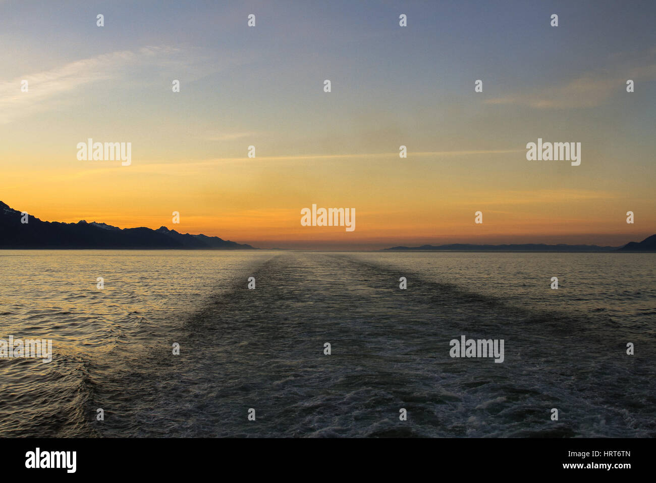 Photo de coucher de soleil sur la mer avec des montagnes et nuages Banque D'Images