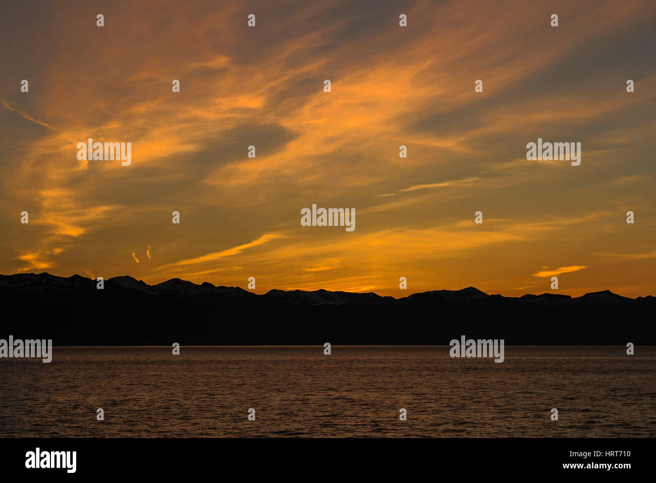 Photo de coucher de soleil sur la mer avec des montagnes et nuages Banque D'Images