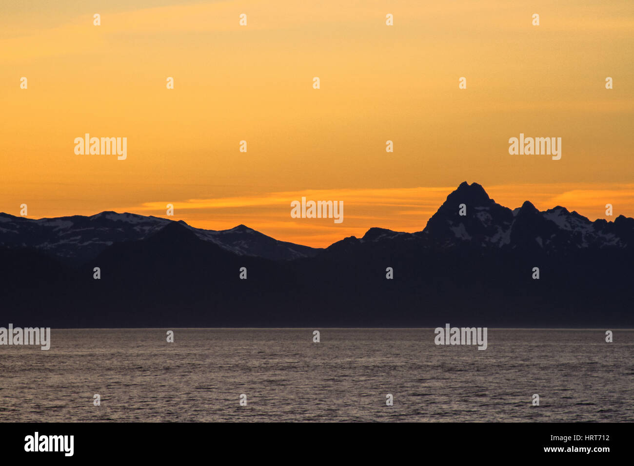 Photo de coucher de soleil sur la mer avec des montagnes et nuages Banque D'Images