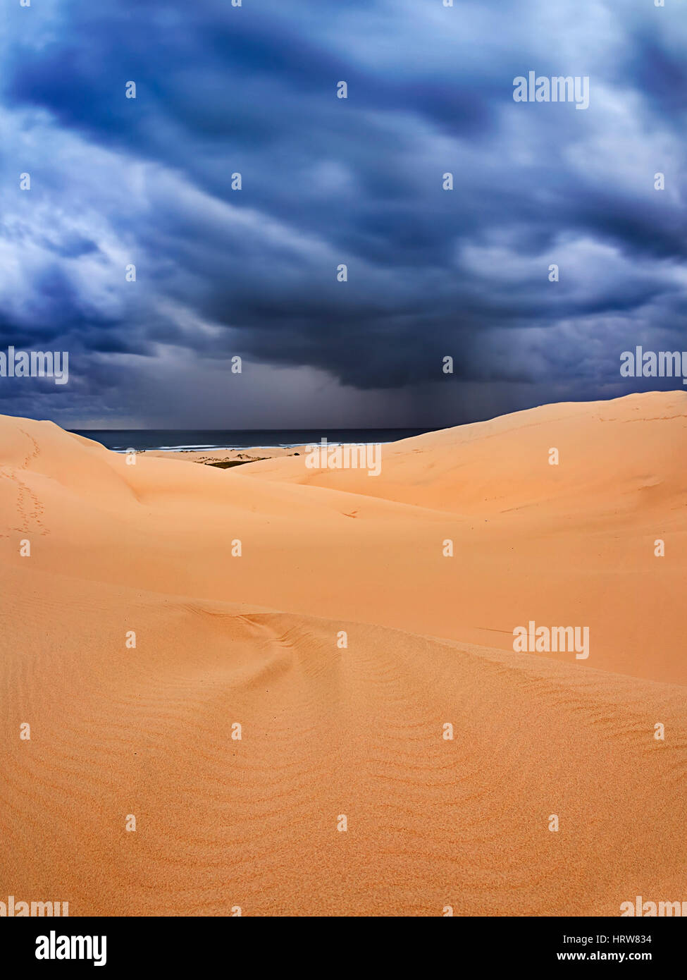 De gros nuages d'orage et de la pluie de l'océan Pacifique sur les dunes de sable de Stockton Beach au coucher du soleil avec motif de vent sur le sable masses Banque D'Images