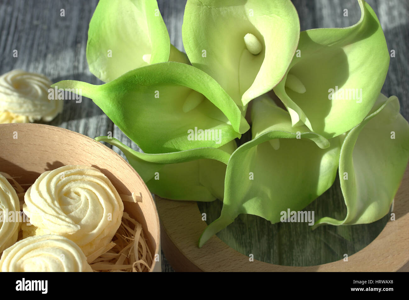 Bouquet de callas jaune vert avec des guimauves dans une boîte ronde en bois gris sur un fond de bois Banque D'Images