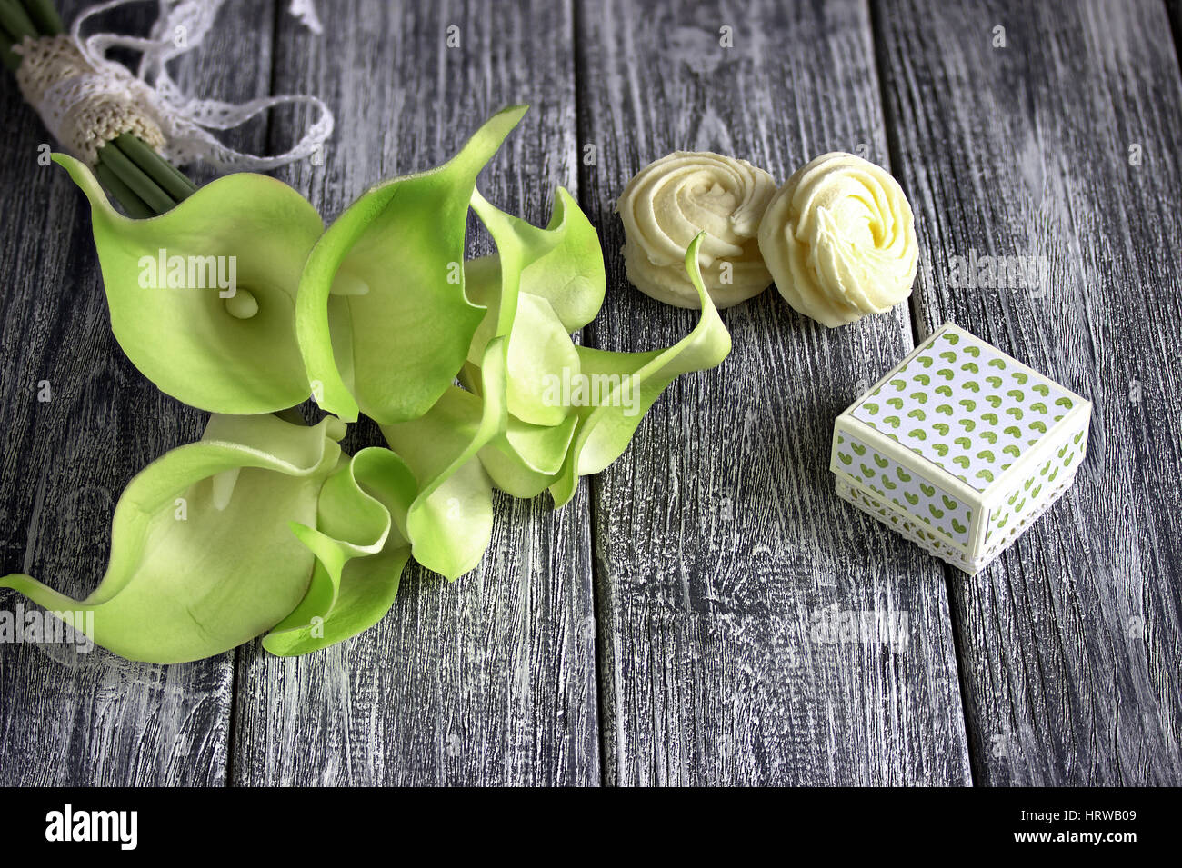 Bouquet de lis calla jaune vert avec des guimauves et boîte en carton gris sur un fond de bois Banque D'Images