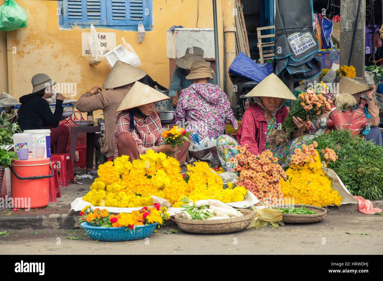 Hoi An, Vietnam - le 14 mars : Les femmes vietnamiennes en chapeau conique vente de fleurs au marché de rue Banque D'Images
