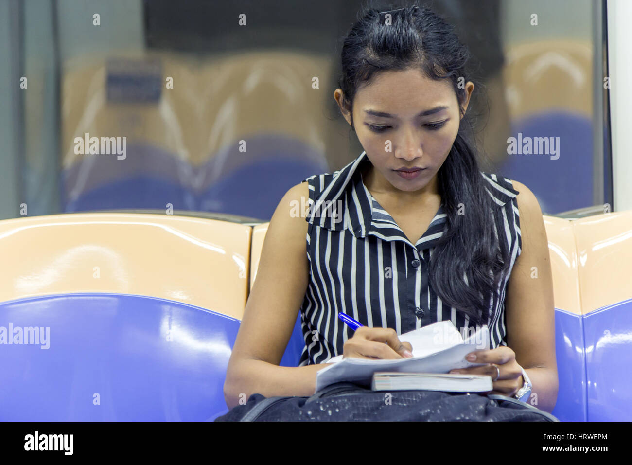 Visualiser les documents touristiques de l'Asie dans le métro. Femme écrit sur un papier en montant le métro. Fille va en train et l'étude de ses notes. Banque D'Images