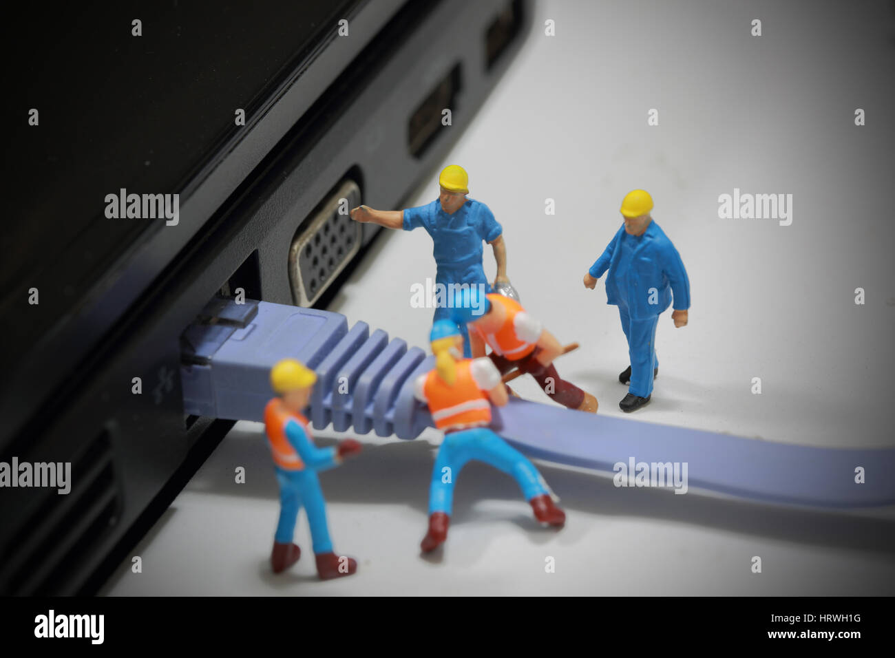 Portrait de l'ingénieur miniature et travailleur installer câble réseau à l'ordinateur et l'utilisation d'arrière-plan d'affaires. Banque D'Images