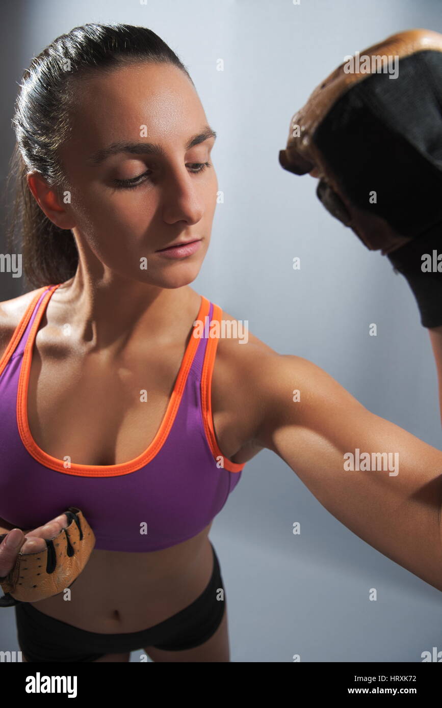 Belle jeune femme sportive flexing biceps gros plan sur fond gris Banque D'Images